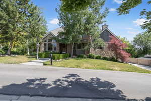 View of front of home with a chimney, a front lawn, and stone siding