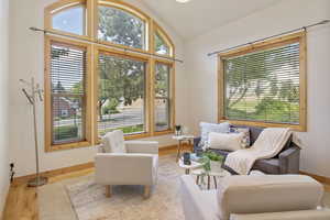 Living area featuring vaulted ceiling, plenty of natural light, and wood finished floors