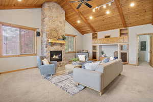 Living room with light carpet, a wooden ceiling with exposed beams, a ceiling fan, and a fireplace.