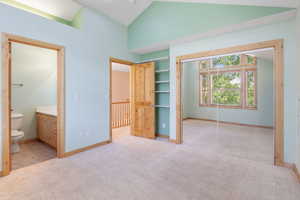 Upstairs bedroom with a closet, carpet flooring, ensuite bathroom, and high vaulted ceiling