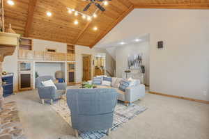 Living room with wood ceiling, light colored carpet, a ceiling fan, and high vaulted ceiling