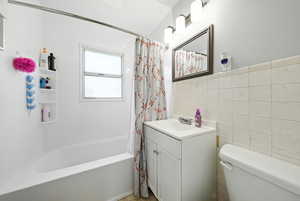 Bathroom featuring vanity, tile walls, and shower / bath combination with curtain