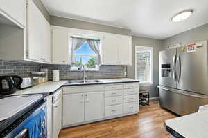 Kitchen with stainless steel appliances, plenty of natural light, white cabinets, and decorative backsplash