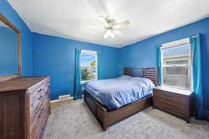 Bedroom featuring a textured ceiling, light colored carpet, and a ceiling fan