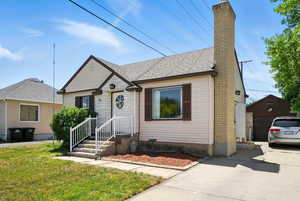 Bungalow with a chimney, a front lawn, a shingled roof, and driveway
