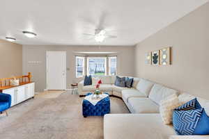 Carpeted living room with a ceiling fan and baseboards