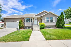 View of front facade featuring a front yard, a garage, and concrete driveway
