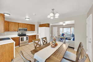 Dining space featuring light tile patterned floors, a chandelier, and a ceiling fan