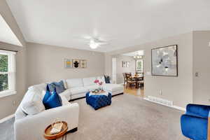Living area with ceiling fan, carpet flooring, and a chandelier