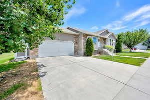 View of front of home featuring a garage, a front lawn, concrete driveway, and brick siding