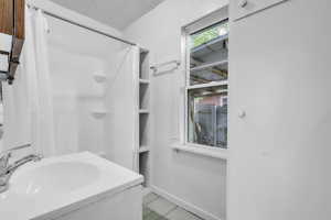 Bathroom featuring tile patterned floors, curtained shower, and vanity