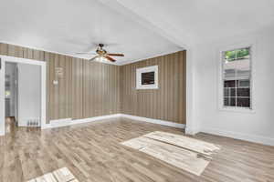Spare room featuring a ceiling fan, wood walls, and wood finished floors