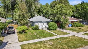 View of front of house featuring a front yard, driveway, a shingled roof, and a chimney