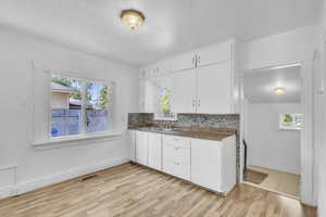 Kitchen with plenty of natural light, white cabinets, and light wood-style floors