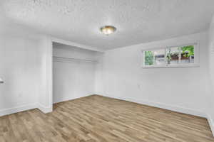 Bedroom #2 featuring light wood-style floors, a textured ceiling, and a closet