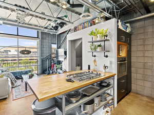 Kitchen with stainless steel appliances, concrete flooring, wooden counters, and open shelves