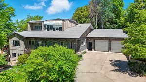 View of front facade with roof with shingles, a garage, and driveway