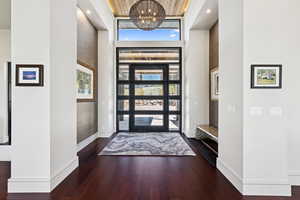 Entryway featuring a towering ceiling, wood finished floors, and a chandelier