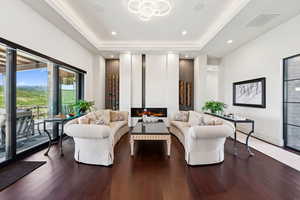 Living area featuring a tray ceiling, a glass covered fireplace, wood finished floors, and recessed lighting