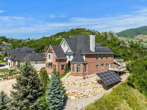 Rear view of property with ground mounted solar panels, a chimney, and brick siding