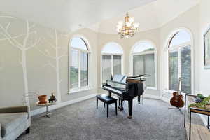 Living area with a chandelier, carpet flooring, and lofted ceiling