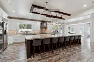 Kitchen featuring plenty of natural light, light wood-style flooring, custom range hood, beam ceiling, and recessed lighting