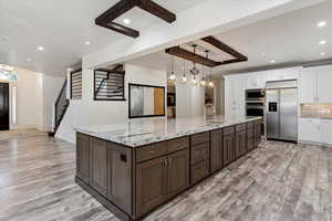 Kitchen with built in appliances, light wood-style flooring, white cabinetry, recessed lighting, and dark brown cabinetry