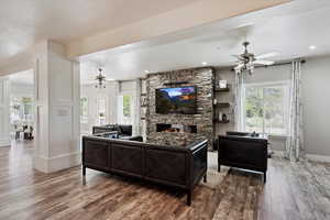 Living area featuring a ceiling fan, wood finished floors, a fireplace, a textured ceiling, and recessed lighting