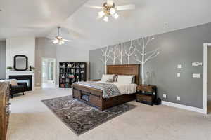 Bedroom with carpet flooring, a glass covered fireplace, high vaulted ceiling, and ceiling fan