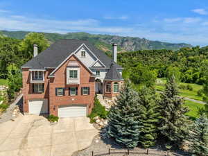 View of front of house featuring a chimney, driveway, an attached garage, a mountain view, and brick siding