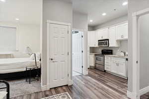 Kitchen with stainless steel appliances, wood finished floors, white cabinetry, and recessed lighting