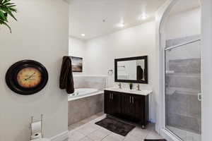 Bathroom featuring tile patterned flooring, a garden tub, a stall shower, and double vanity