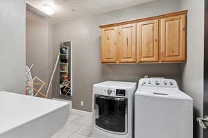 Laundry area with cabinet space, washing machine and dryer, and light tile patterned flooring