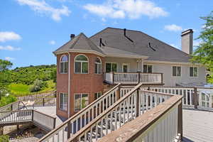Rear view of house with a chimney, stairs, a wooden deck, and brick siding