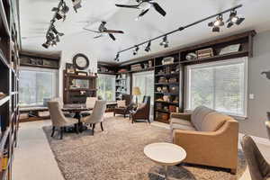 Carpeted living area featuring track lighting, a ceiling fan, and plenty of natural light