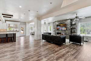 Living area with light wood-style flooring, a ceiling fan, a fireplace, plenty of natural light, and recessed lighting