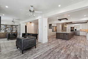 Living area featuring ceiling fan, light wood-style flooring, recessed lighting, and a chandelier