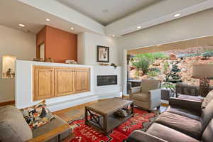 Living room featuring recessed lighting, a glass covered fireplace, and stone finish floors