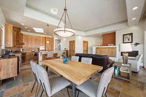 Dining area featuring stone tile flooring, recessed lighting, a tray ceiling, and a skylight