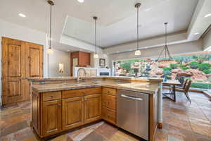 Kitchen featuring stainless steel dishwasher, stone tile flooring, a raised ceiling, and recessed lighting