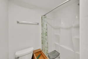 Full bath featuring toilet and a shower with curtain inside detached garage
