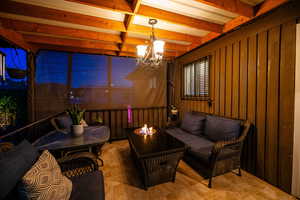 Sunroom / solarium featuring a chandelier and beamed ceiling