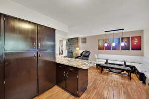 Kitchen featuring  dark brown cabinets, a peninsula, and light stone countertops