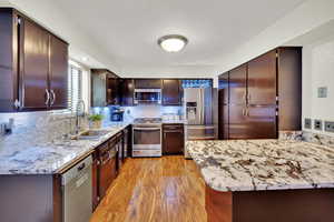 Kitchen with appliances with stainless steel finishes, decorative backsplash, and light stone countertops