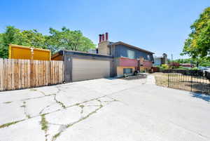 View of property exterior featuring a chimney, a garage, and concrete driveway