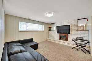 Carpeted living area featuring a brick fireplace and wood walls