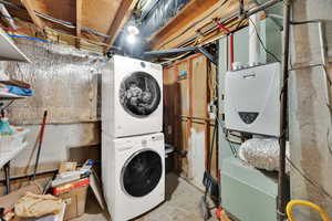 Washroom featuring stacked washer / dryer and water heater