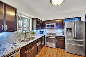 Kitchen featuring appliances with stainless steel finishes, tasteful backsplash, and light stone counters