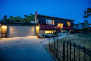 Contemporary house with brick siding, driveway, a chimney, and an attached garage