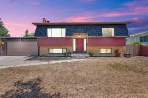 Bi-level home with brick siding, a garage, mansard roof, concrete driveway, and a shingled roof